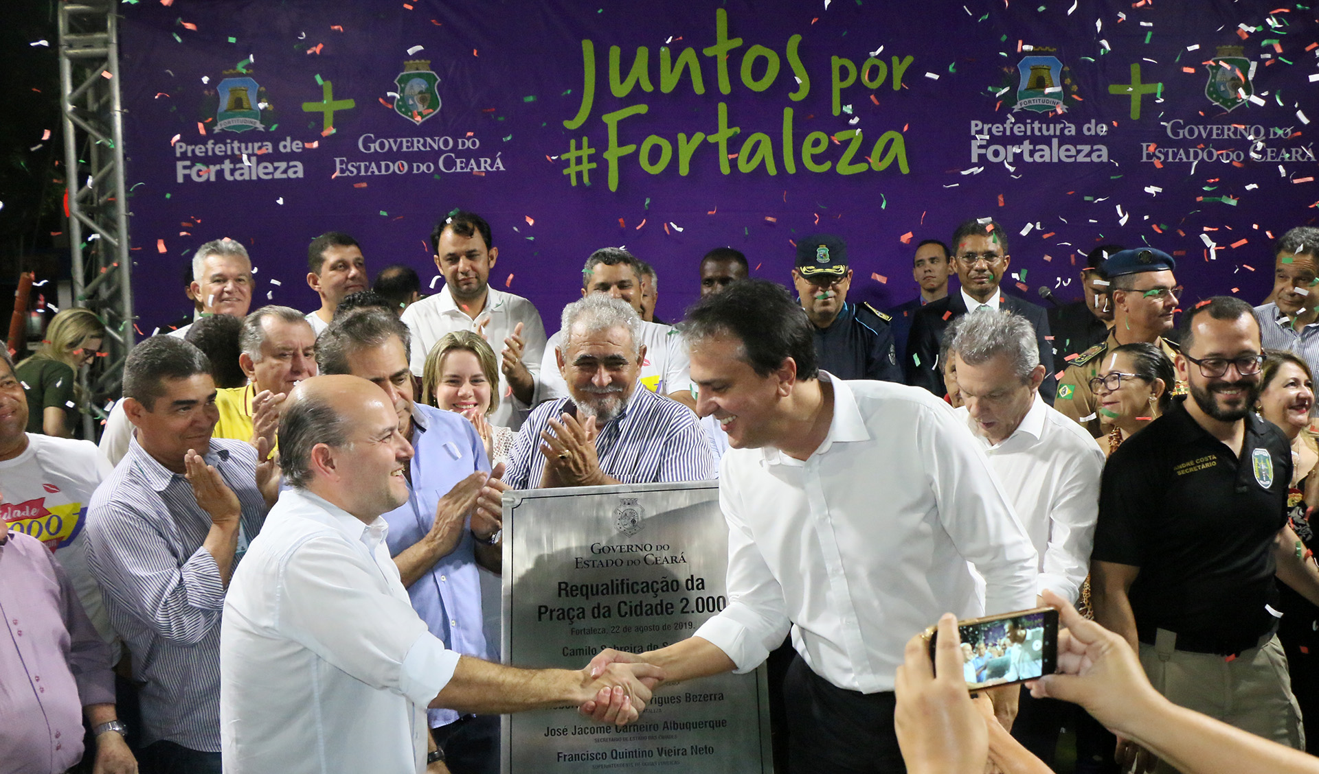 prefeito roberto cláudio e governador camilo santana apertam as mãos num palco